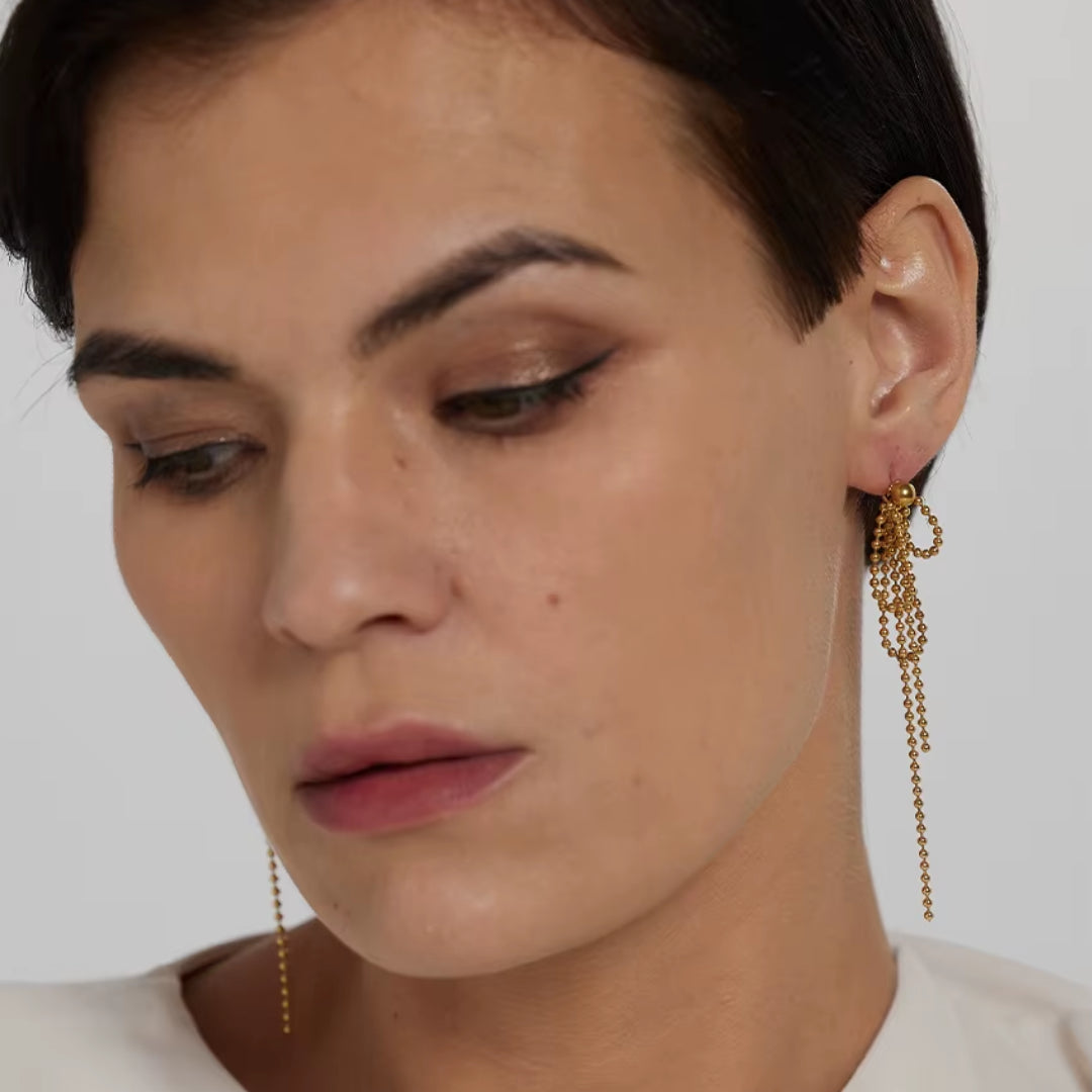 https://lenorajewelry.com/pendientes-esfera-doradapendientes colgantes geométricos, pendientes dorados ligeros, joyería de acero inoxidable, pendientes modernos para mujer, aretes largos elegantes, accesorios femeninos sofisticados, pendientes de cuentas doradas, joyería resistente y elegante
