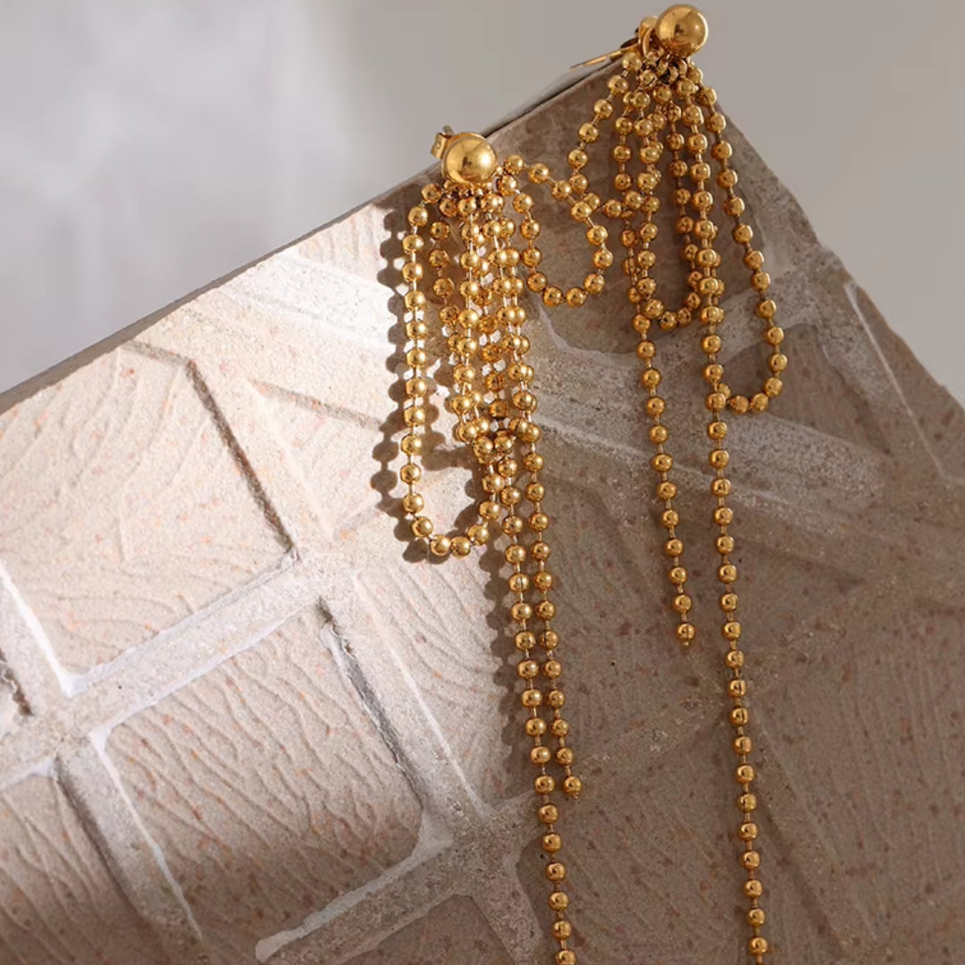 https://lenorajewelry.com/pendientes-esfera-doradapendientes colgantes geométricos, pendientes dorados ligeros, joyería de acero inoxidable, pendientes modernos para mujer, aretes largos elegantes, accesorios femeninos sofisticados, pendientes de cuentas doradas, joyería resistente y elegante